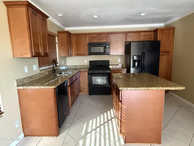 a kitchen with stainless steel appliances granite countertop a stove top oven a sink and a refrigerator