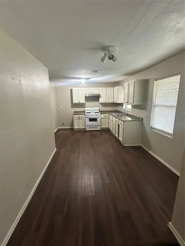 a kitchen with a sink dishwasher a stove and white countertops with wooden floor
