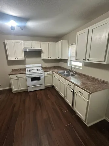 a kitchen with stainless steel appliances granite countertop a stove a sink and white cabinets