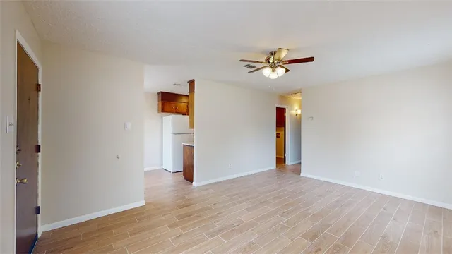 an empty room with wooden floor and ceiling fan