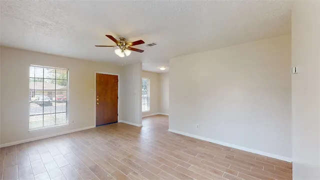 a view of an empty room with a window and wooden floor