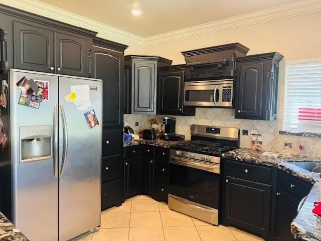 a kitchen with granite countertop a refrigerator stove and microwave
