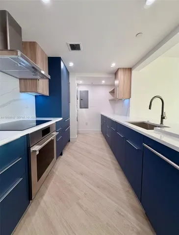 a large kitchen with stainless steel appliances a large counter top a stove and a sink