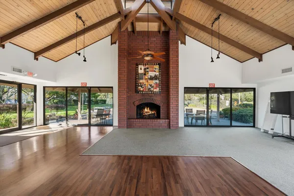 a view of an empty room with wooden floor fireplace and a window