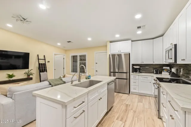 a kitchen with stainless steel appliances granite countertop a refrigerator sink and white cabinets