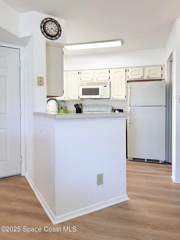 a kitchen with white cabinets and white appliances