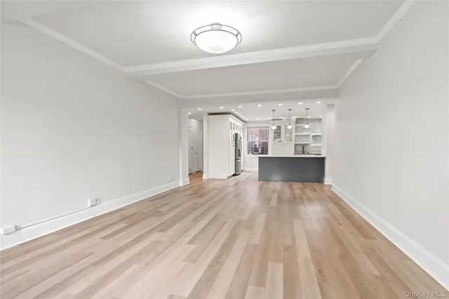a view of a room with wooden floor and kitchen view