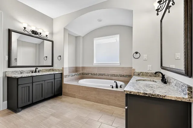 a bathroom with a granite countertop double vanity sink and mirror