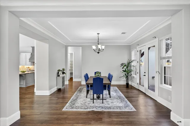 a dining room with wooden floor a chandelier a wooden table and chairs