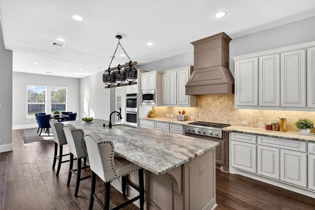 a kitchen with stainless steel appliances granite countertop a kitchen island a stove a table and chairs in it