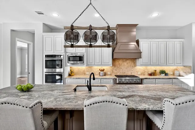 a kitchen with stainless steel appliances granite countertop a sink a stove and a wooden cabinets