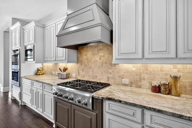a kitchen with stainless steel appliances granite countertop a stove and a white cabinets