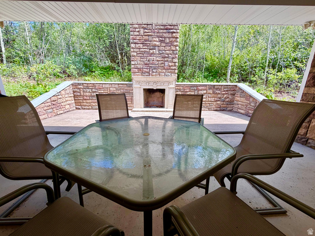 1133 Paris Canyon Road Paris, ID 83261 - Photo 32 of 75 Covered outdoor patio featuring a stone fireplace with a decorative mantel, stone retaining walls, and a concrete floor