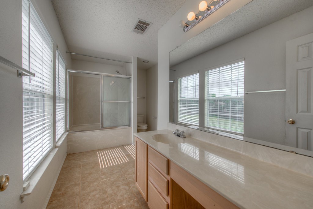 2623 Andres Way Round Rock, TX 78664 - Photo 11 of 15 a bathroom with a granite countertop sink a large mirror and a bathtub next to a window