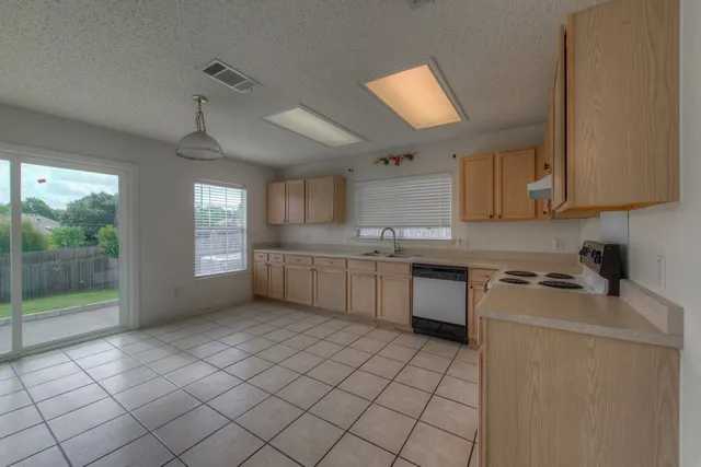 a kitchen with a sink a stove cabinets and a window