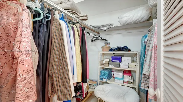 a view of walk in closet with clothes and shoes