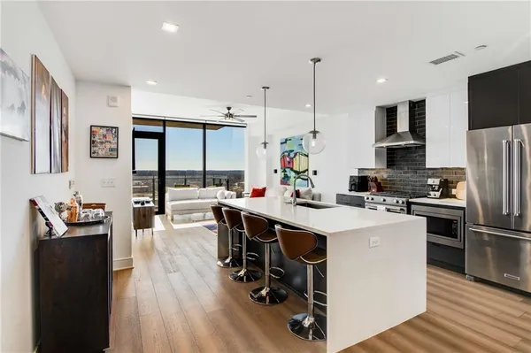 a kitchen with stainless steel appliances a sink a stove a refrigerator cabinets and wooden floor