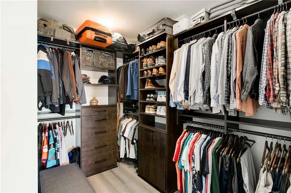 a view of walk in closet with clothes and shoes