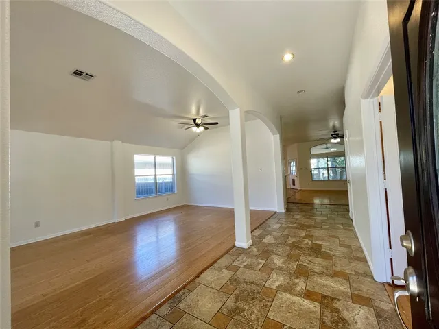 an empty room with wooden floor and windows