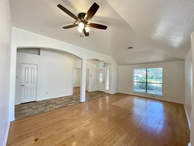 a view of a big room with wooden floor and windows