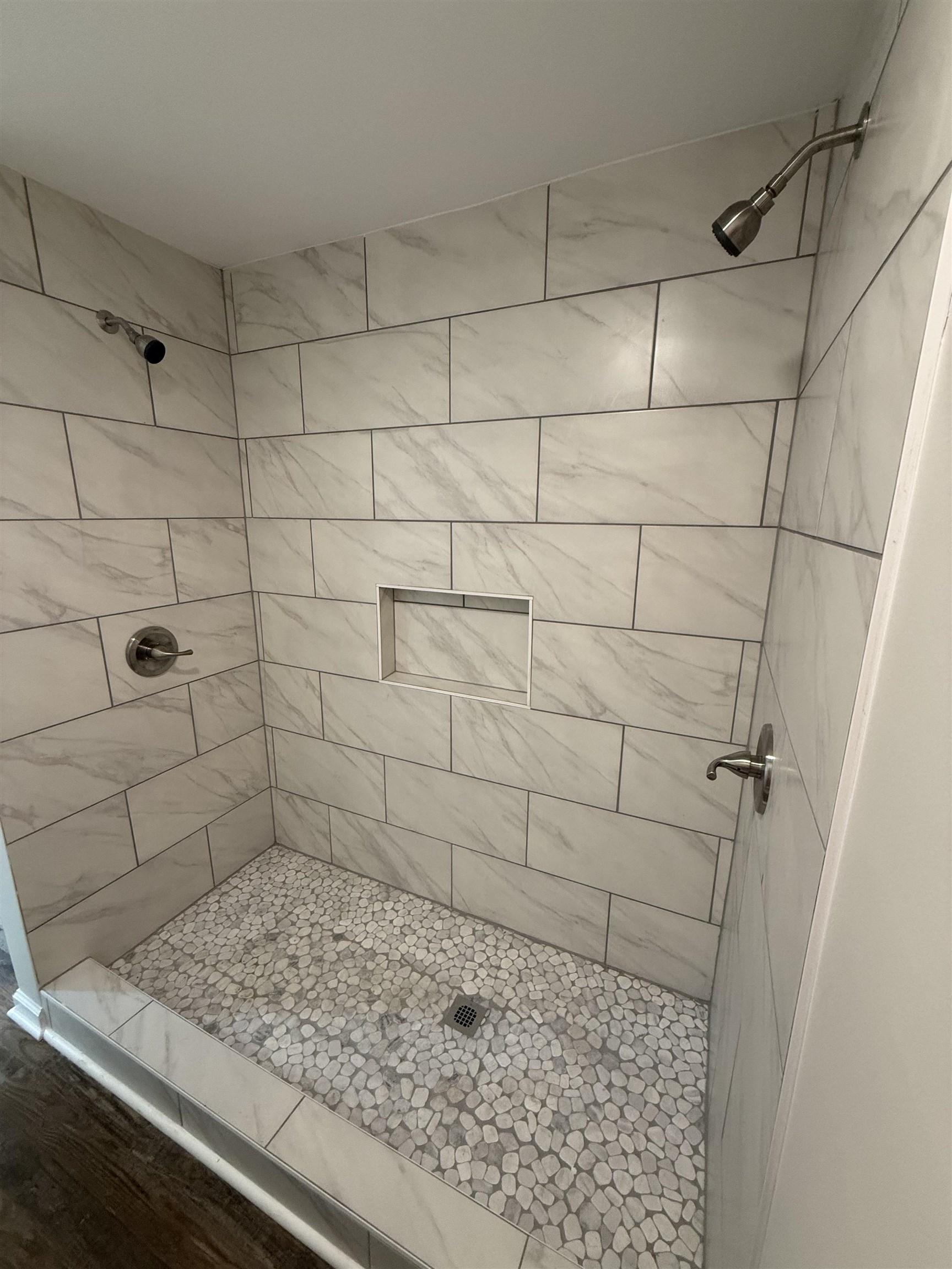 1835 Pleasant Grove Road Moscow, TN 38057 - Photo 16 of 34 Walk-in shower featuring dual showerheads, stone pebble flooring, a tiled niche, and large format wall tiling