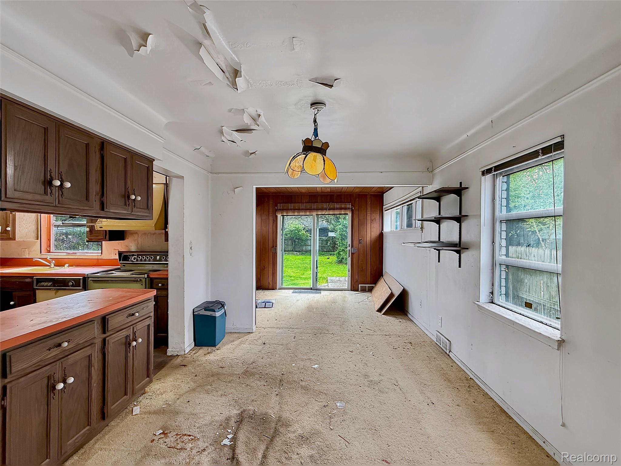 Kitchen featuring healthy amount of natural light, range with electric stovetop, wood counters, and dark wood finish cabinetry