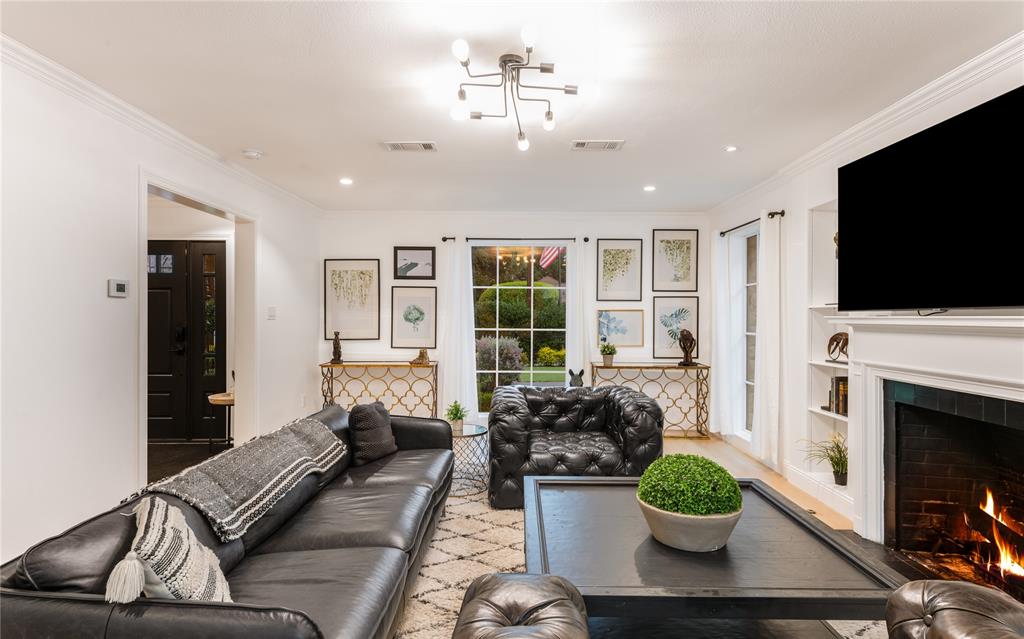 5947 Lupton Drive Dallas, TX 75225 - Photo 33 of 39 Living area with ornamental molding, a warm lit fireplace, wood finished floors, built in shelves, and recessed lighting