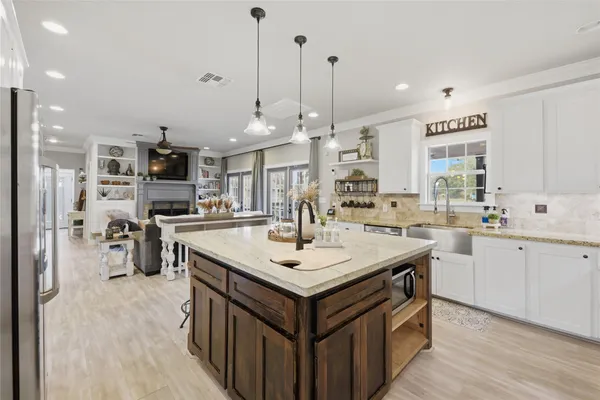 a large kitchen with kitchen island a stove a table a sink and a living room view