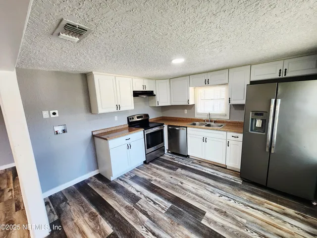a kitchen with a sink cabinets stainless steel appliances and a window