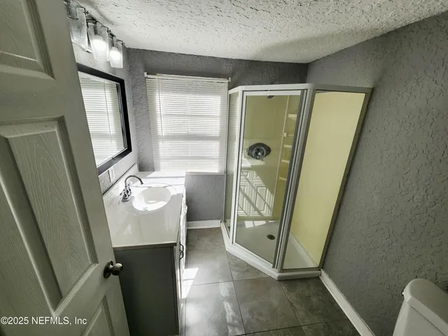 a bathroom with a glass door shower and a sink