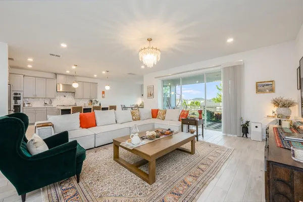 a living room with furniture kitchen view and a chandelier