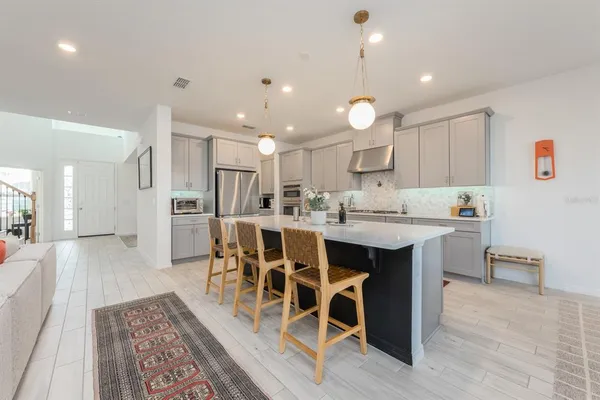 a kitchen with stainless steel appliances kitchen island granite countertop a dining table chairs and white cabinets