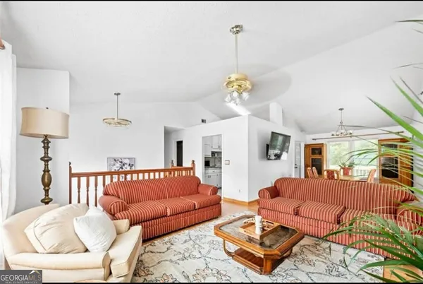 a living room with furniture kitchen view and a chandelier