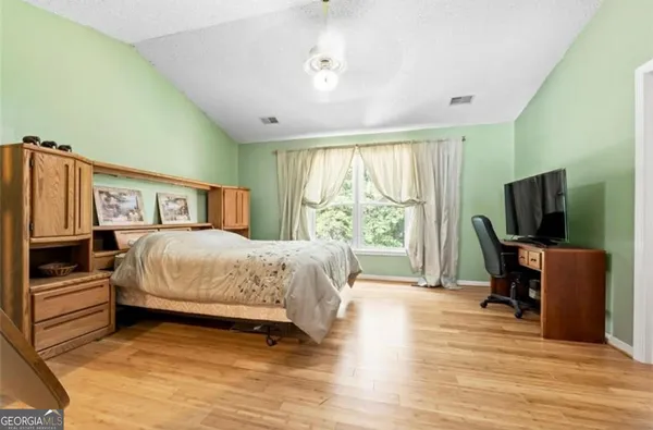 a spacious bedroom with a bed and a flat screen tv