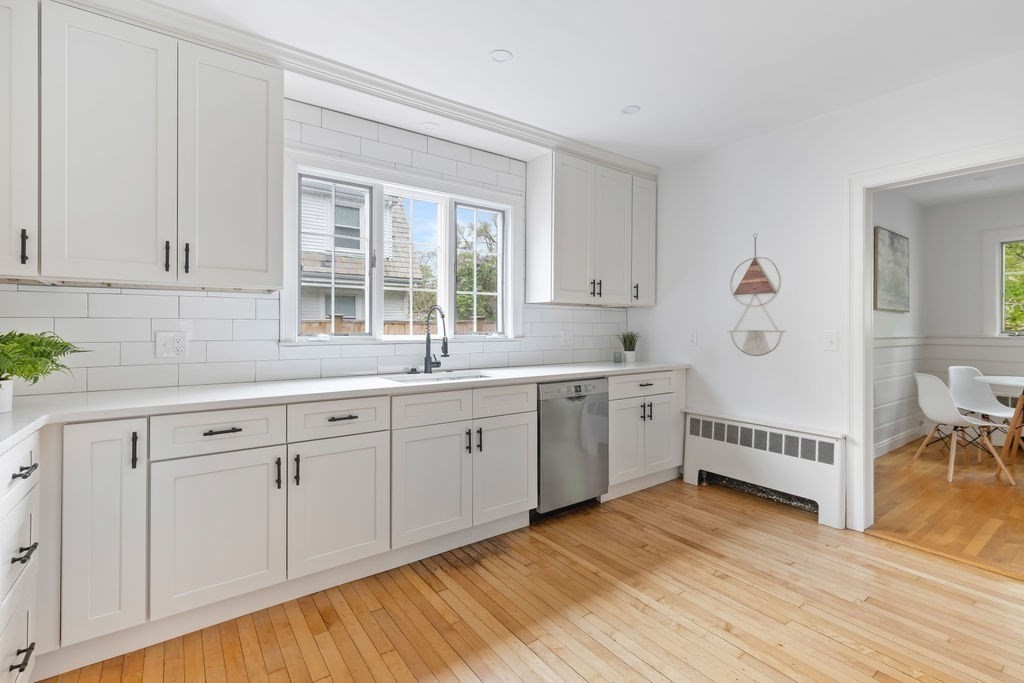 311 Clark Road Brookline, MA 02445 - Photo 8 of 26 a large white kitchen with a window wooden floor and stainless steel appliances