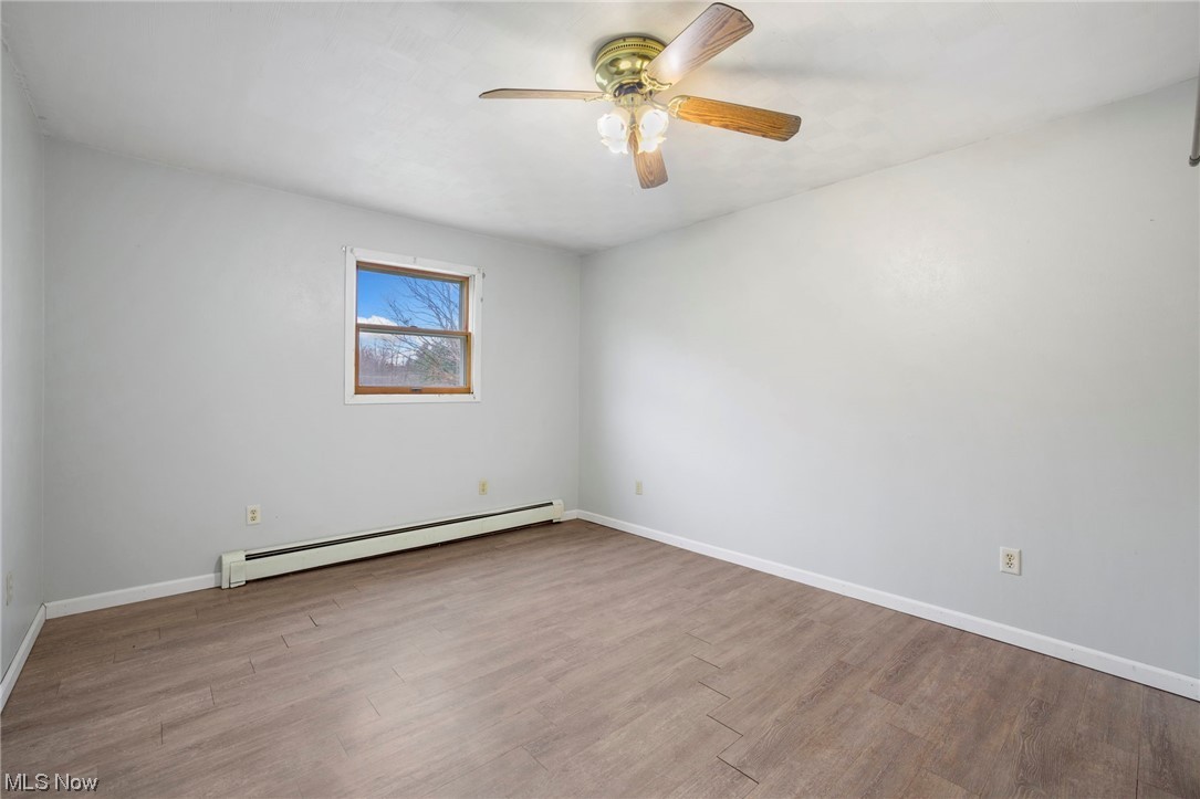 6322 Homeworth Road Homeworth, OH 44634 - Photo 14 of 36 Spare room featuring light wood-type flooring, ceiling fan, and a baseboard radiator