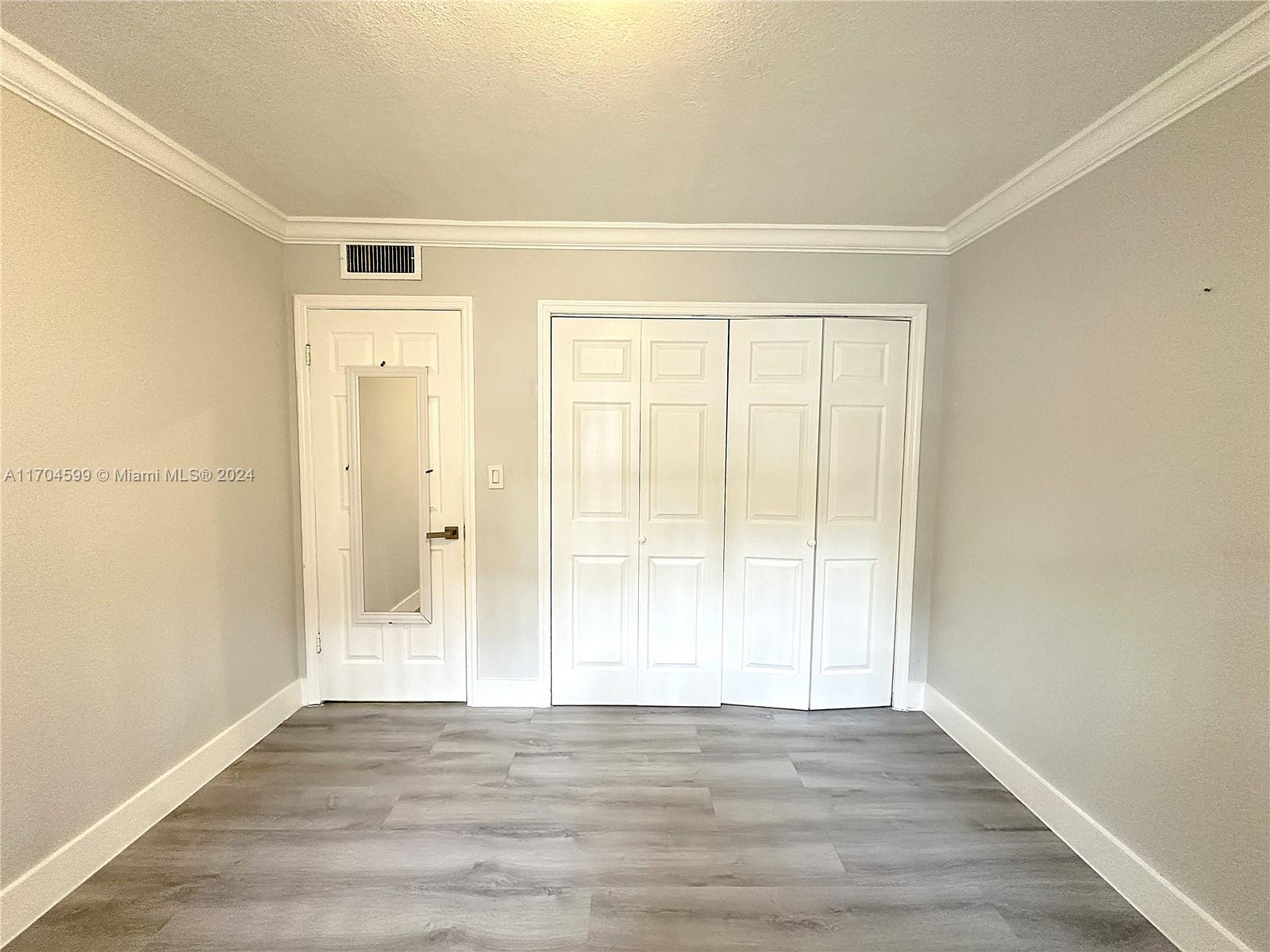 7101 Southwest 89th Court, Unit 110 Miami, FL 33173 - Photo 13 of 16 a view of an empty room with wooden floor and a window