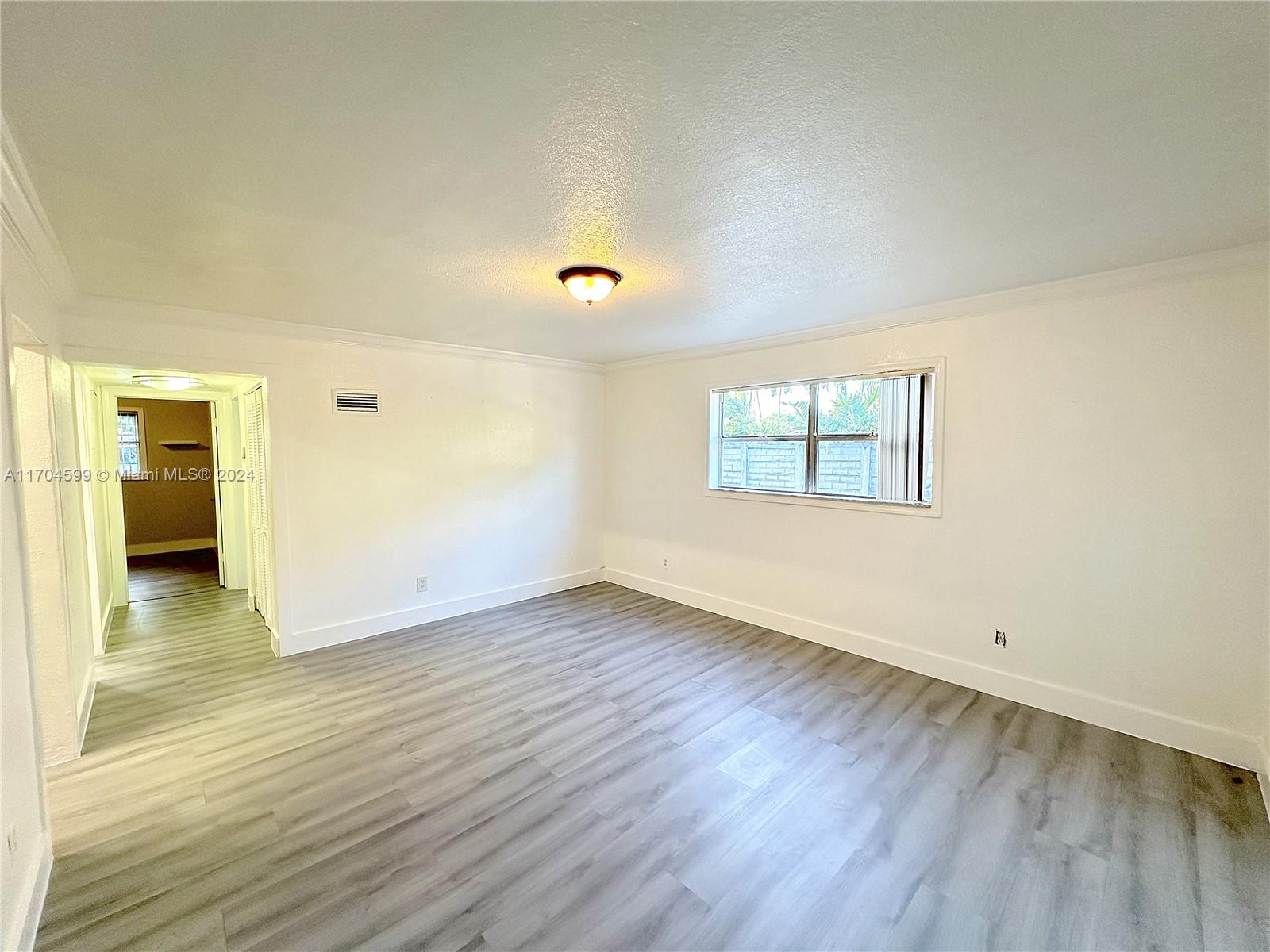 7101 Southwest 89th Court, Unit 110 Miami, FL 33173 - Photo 2 of 16 an empty room with wooden floor and windows