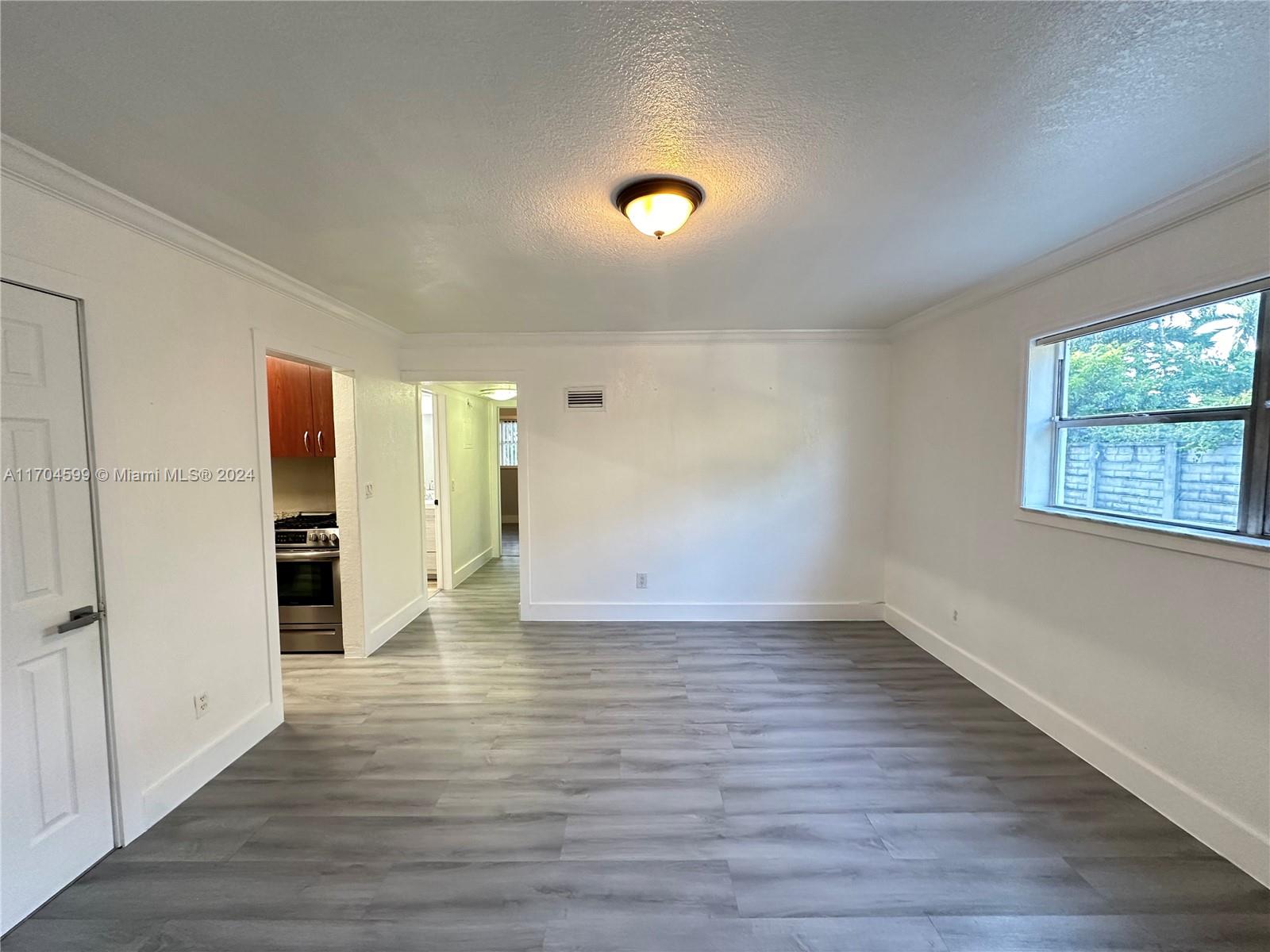 7101 Southwest 89th Court, Unit 110 Miami, FL 33173 - Photo 3 of 16 a view of an empty room with wooden floor and a window