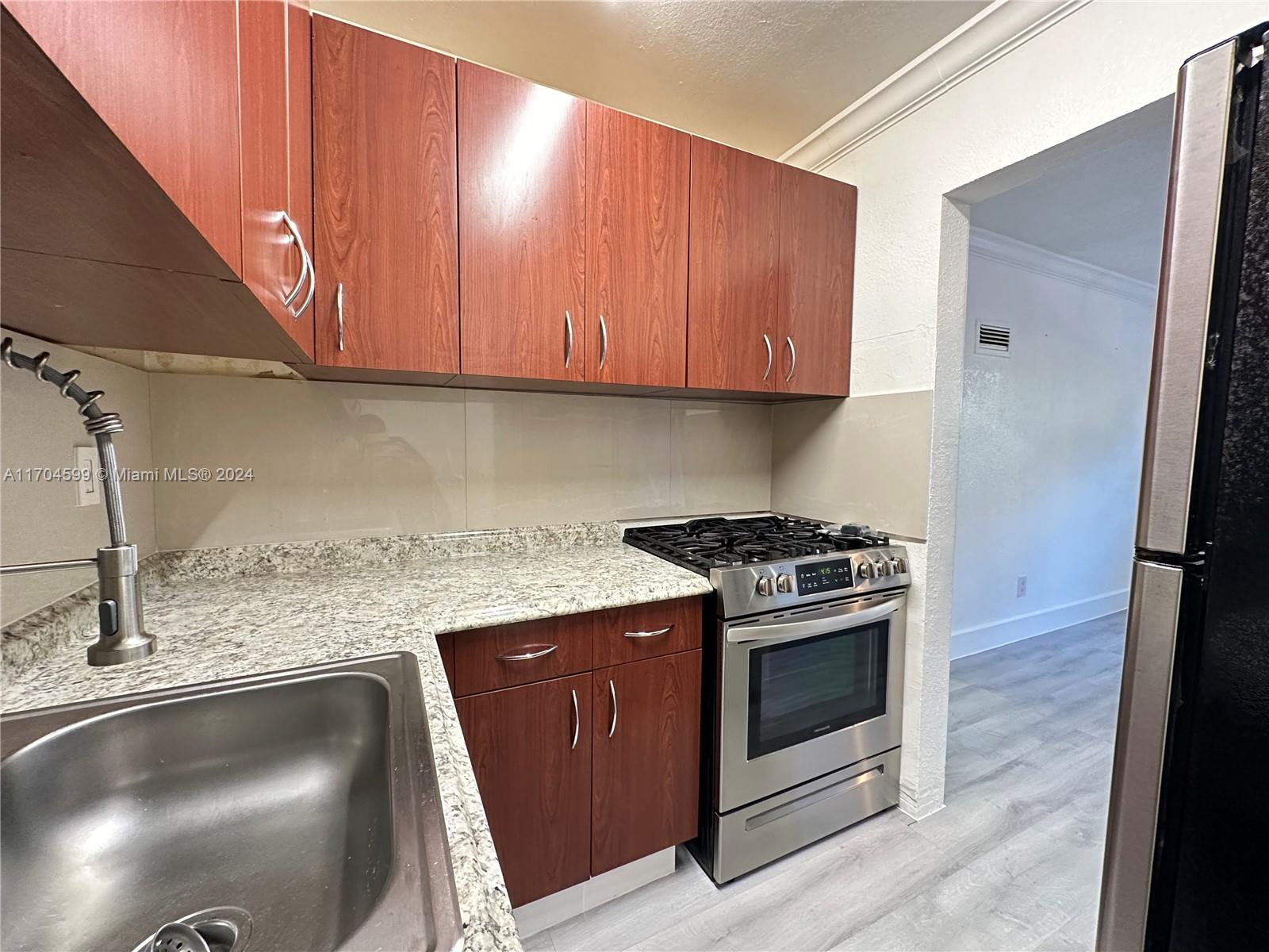 7101 Southwest 89th Court, Unit 110 Miami, FL 33173 - Photo 5 of 16 a kitchen with granite countertop a stove top oven a sink and dishwasher