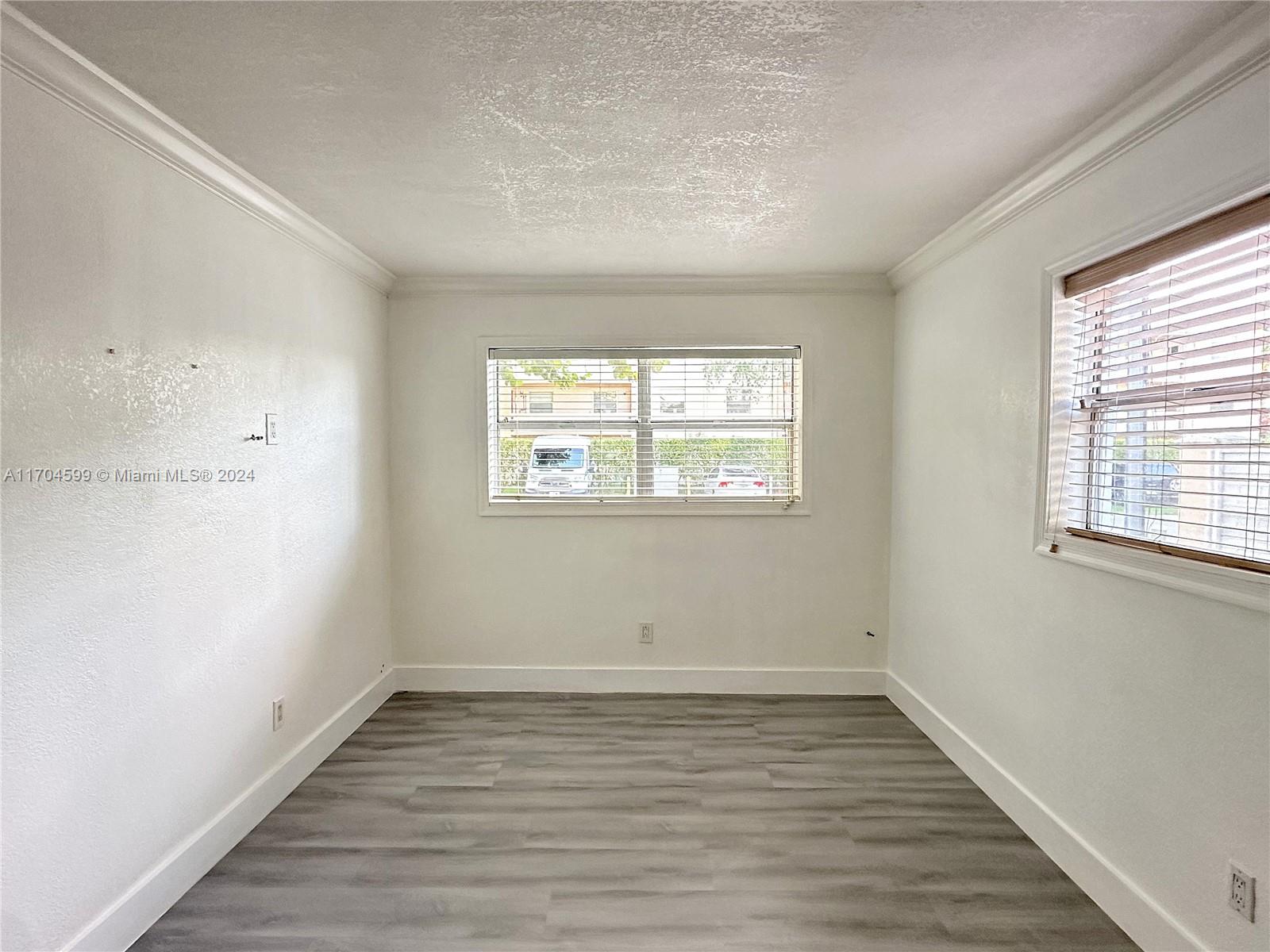 7101 Southwest 89th Court, Unit 110 Miami, FL 33173 - Photo 9 of 16 an empty room with wooden floor and windows