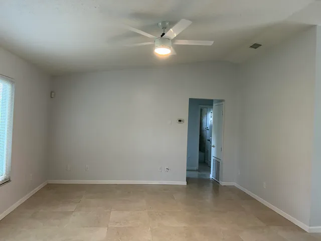an empty room with a ceiling fan and a window