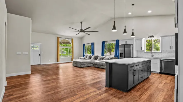 a kitchen with stainless steel appliances granite countertop a refrigerator a oven a sink dishwasher and white cabinets with wooden floor