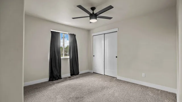 a view of an empty room and a chandelier fan