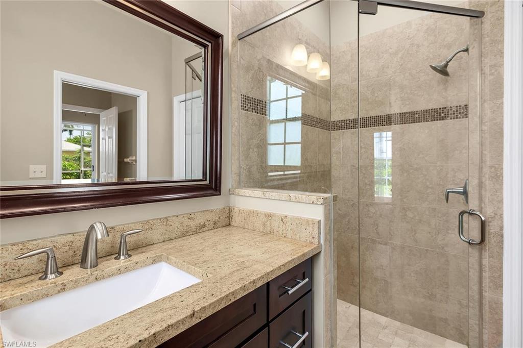2389 Piccadilly Circus Naples, FL 34112 - Photo 6 of 21 a bathroom with a granite countertop sink mirror and a shower