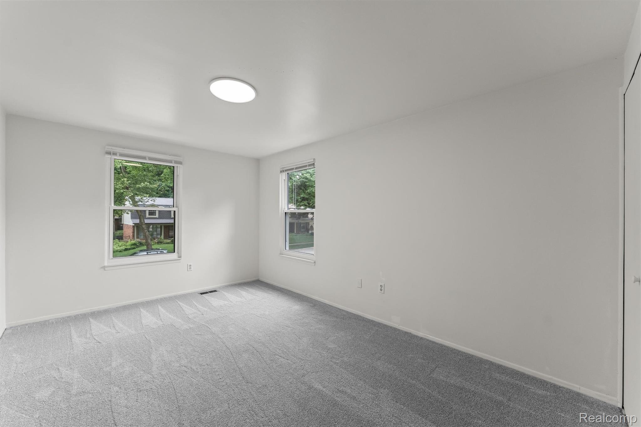 2118 Rutgers Drive Troy, MI 48085 - Photo 18 of 39 Bright room featuring two windows, light grey carpeting, white walls, and a ceiling-mounted light fixture