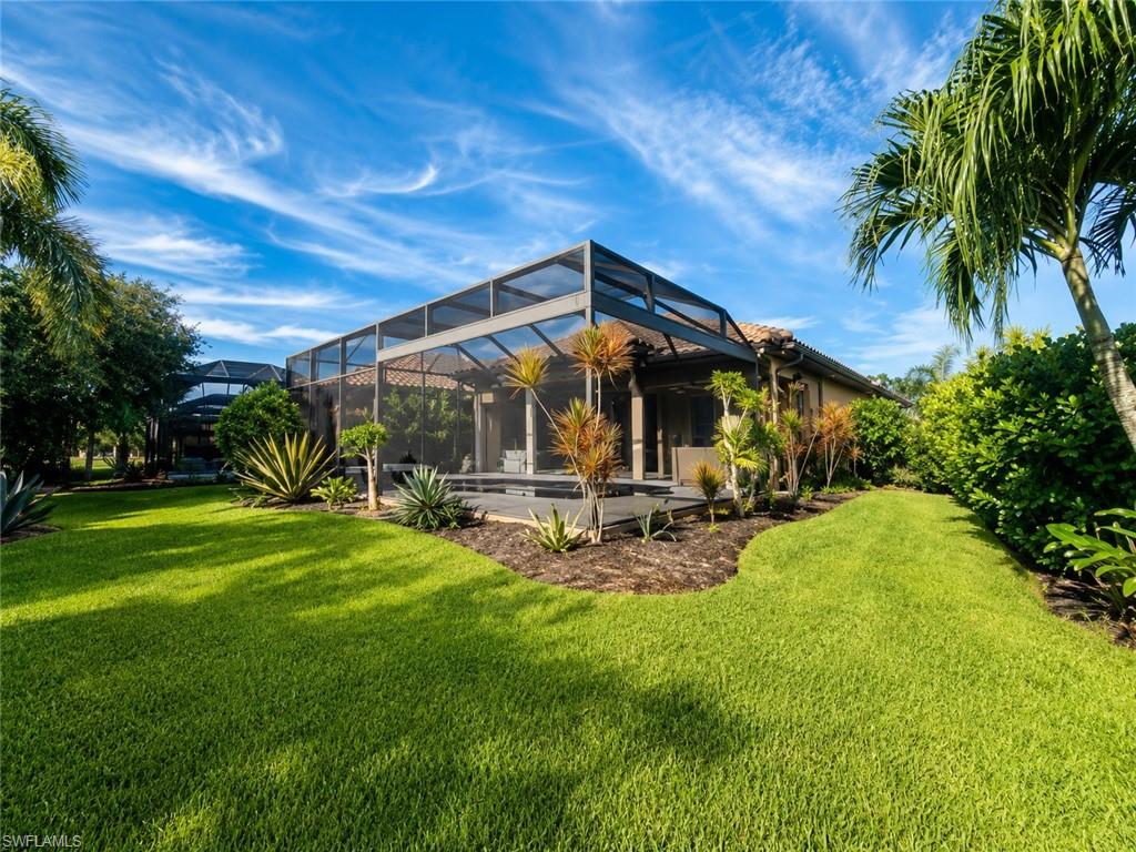 6574 Amarone Lane Naples, FL 34113 - Photo 28 of 44 a view of a backyard with table and chairs under an umbrella