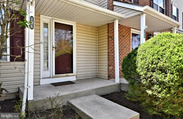 a view of a white house with a large windows and flower plants