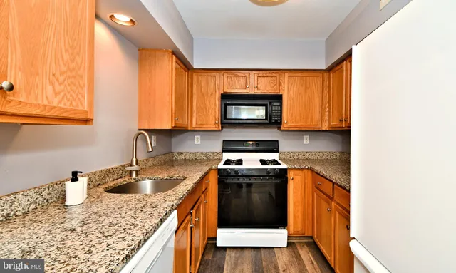 a kitchen with granite countertop a sink stove and microwave