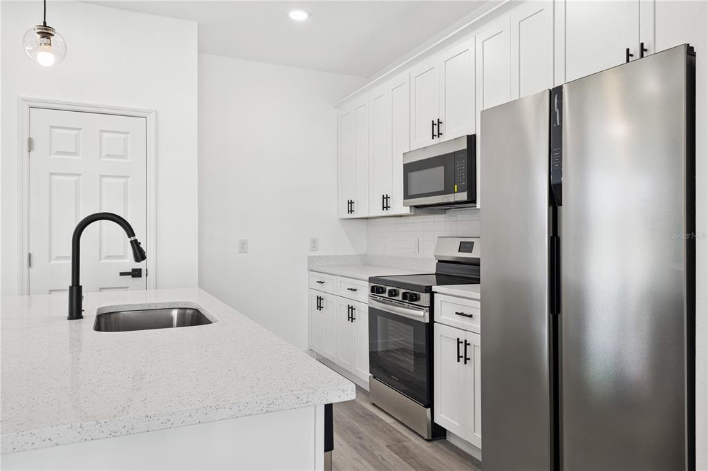 925 Desmoines Way Poinciana, FL 34759 - Photo 19 of 40 a kitchen with stainless steel appliances granite countertop a stove a refrigerator and a sink